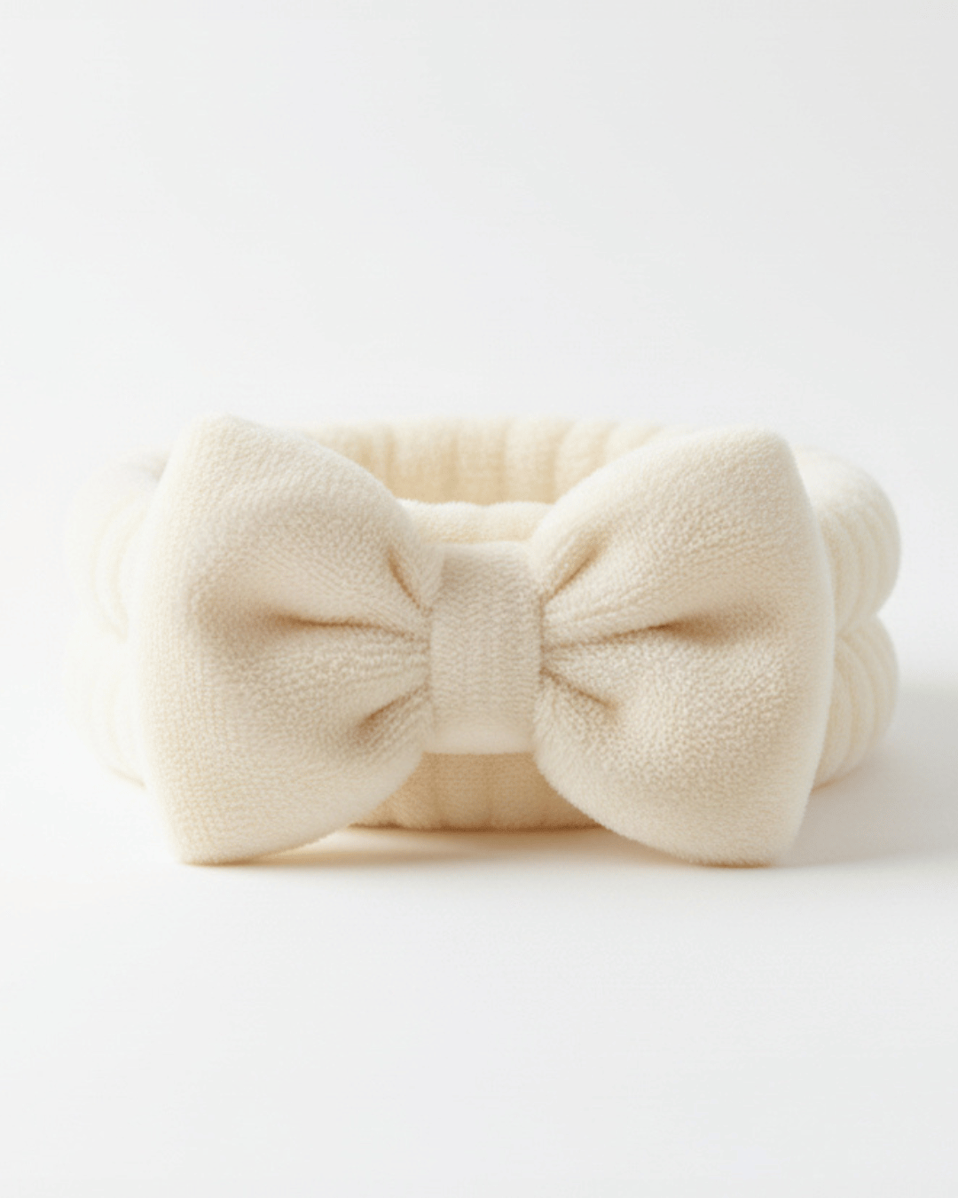 Cream-coloured headband with a large bow, designed for precision dermaplaning, set on a white background 