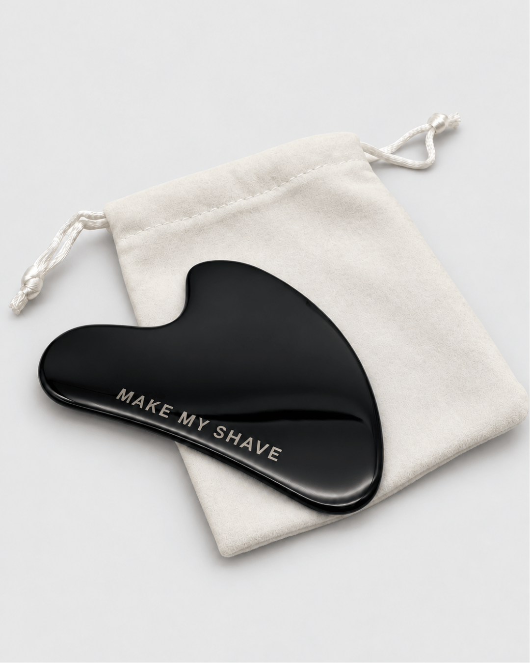 Black Gua Sha by Make My Shave, Australia for facial lymphatic drainage. Sitting on a drawstring pouch.