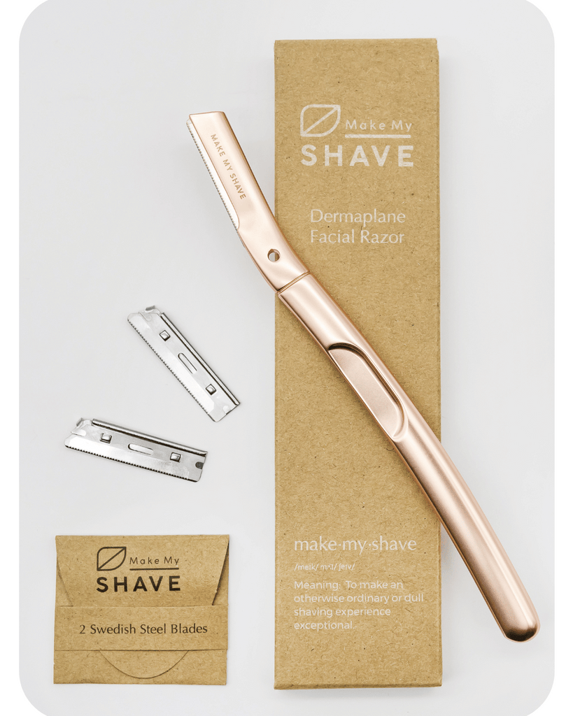 Rose gold dermaplaning tool. The facial razor packaging is eco-friendly with extra blades and a grey background. 