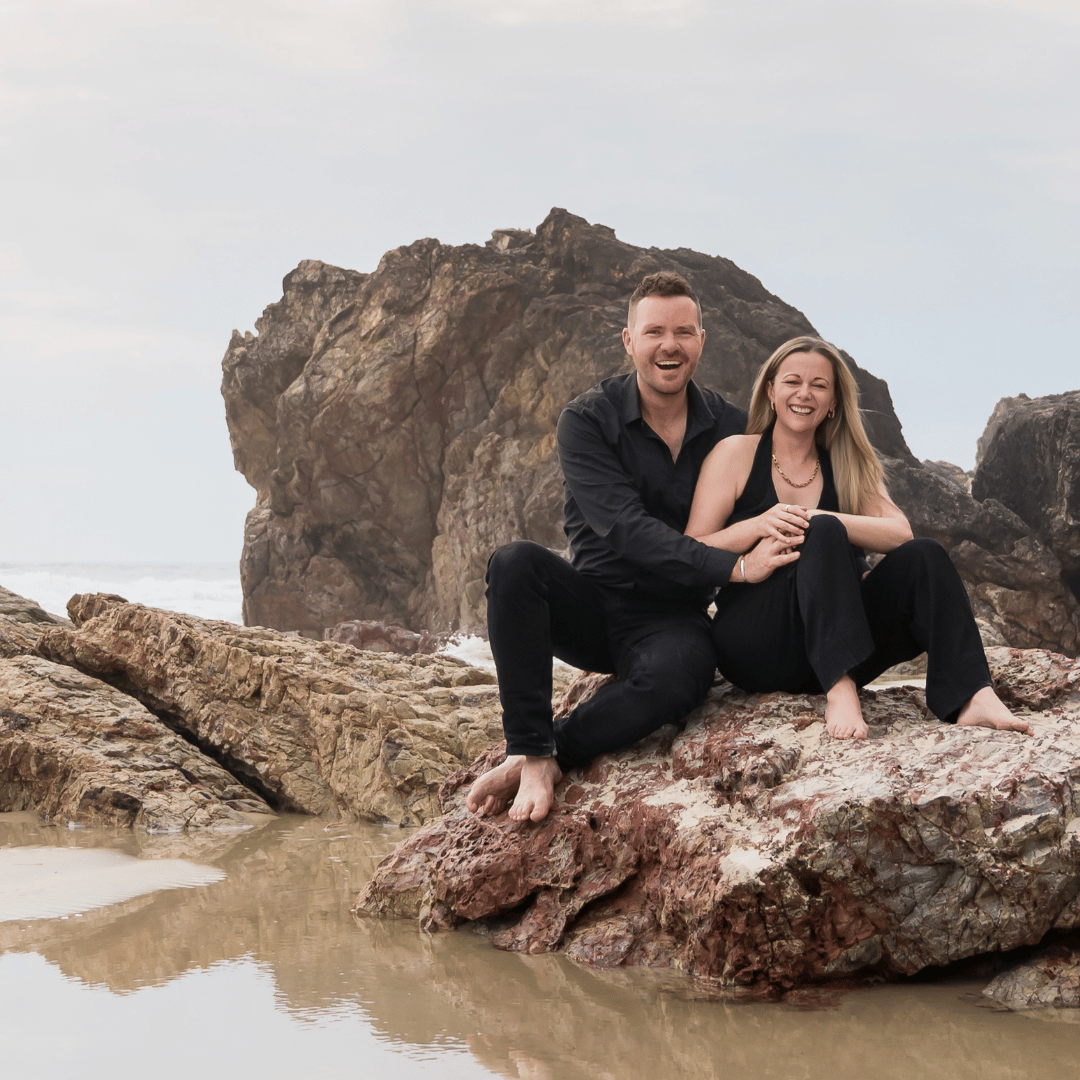 Make My Shave Founders Lindsay and Mike, sitting on rocks in the Gold Coast, Australia. 