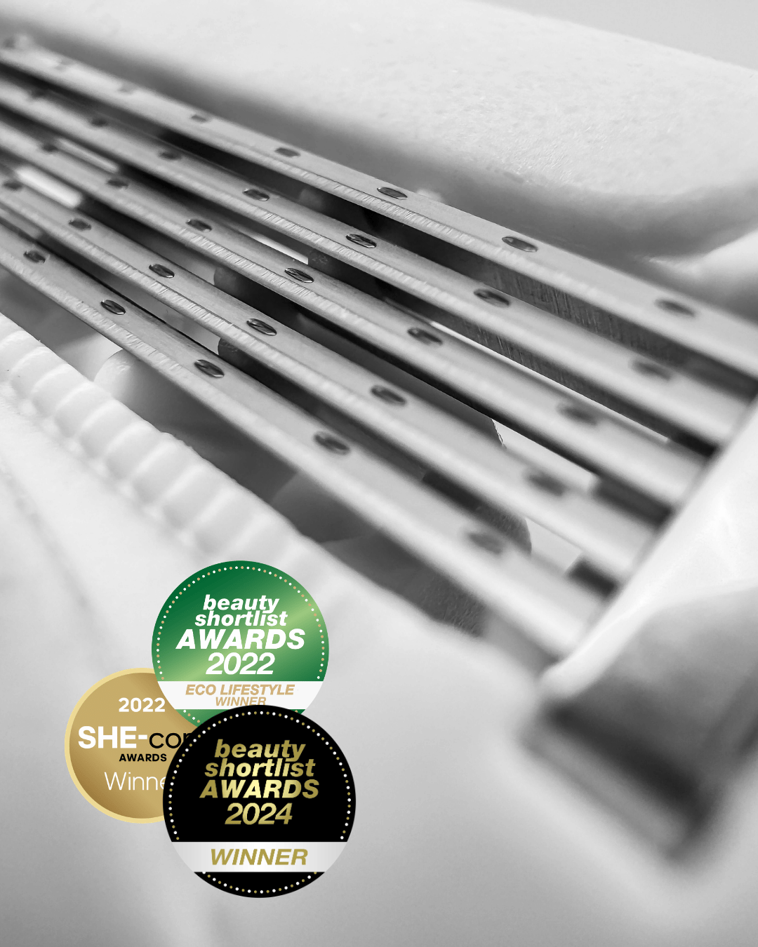 Close-up of 5-blade women's razor with three award badges showing: a green 2022 Beauty Shortlist Award, a gold 2022 SHE Awards Winner, and a black 2024 Beauty Shortlist Award Winner. The brand is Make My Shave.